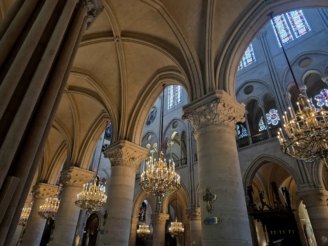 Ornate cathedral interior featuring arched ceilings, stone columns, and chandeliers