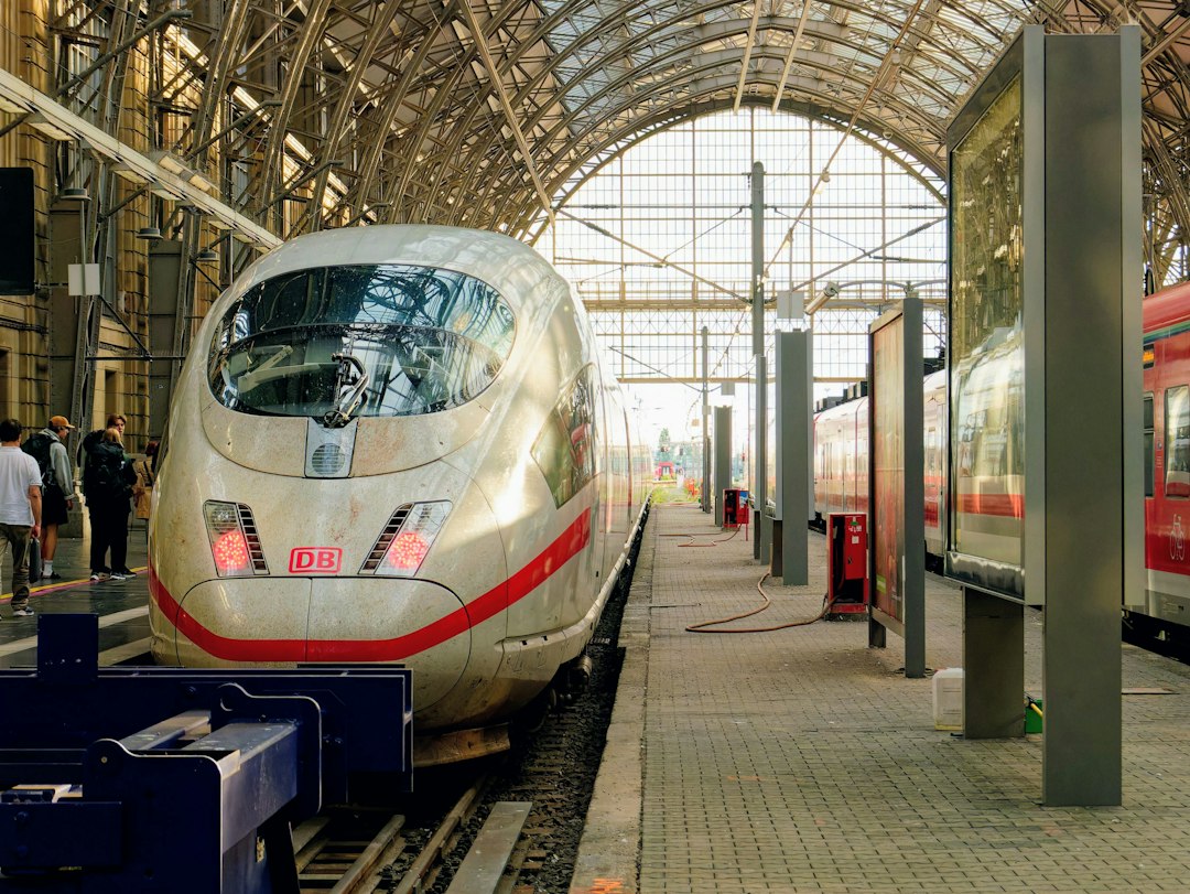 A high-speed ICE train at a platform under a large arched glass roof